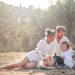 Happy family enjoying a picnic in an olive grove under the sun. Perfect for lifestyle and outdoor themes.